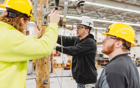 Three electrical line worker students are practicing skills in the classroom